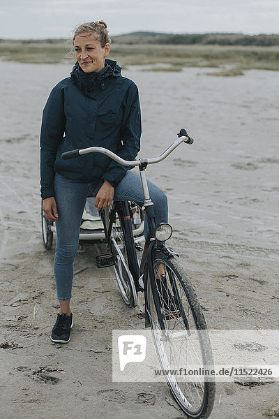 Niederlande  Schiermonnikoog  Frau mit Fahrrad und Anhänger am Strand