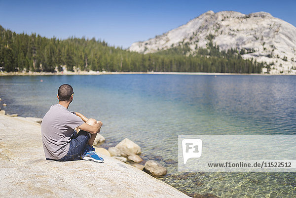 USA  California  Yosemite National Park  man sitting at mountain lake