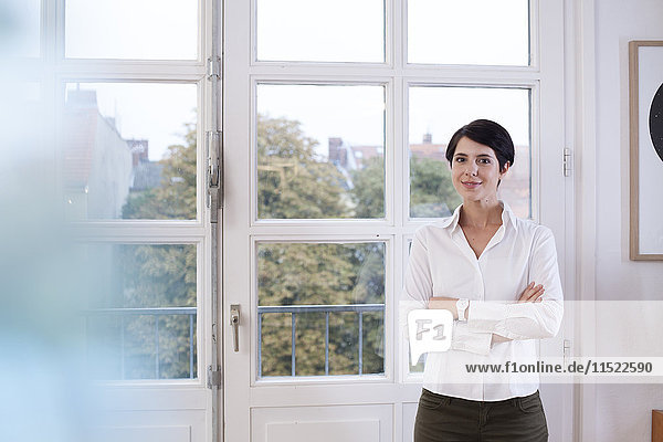 Porträt einer selbstbewussten Frau am Fenster stehend