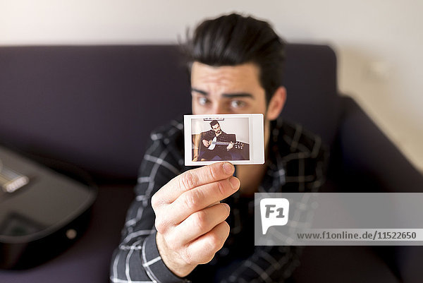 Man showing photography of himself playing guitar