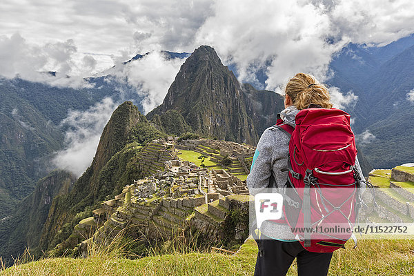 Peru  Anden  Urubamba-Tal  Tourist mit rotem Rucksack bei Machu Picchu mit Berg Huayna Picchu