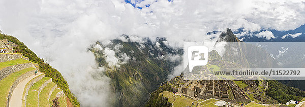 Peru  Andes  Urubamba Valley  Machu Picchu with mountain Huayna Picchu in fog with tourists