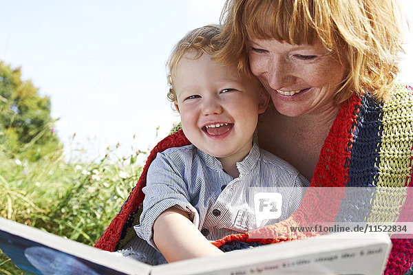 Happy mother and son with picture book in meadow