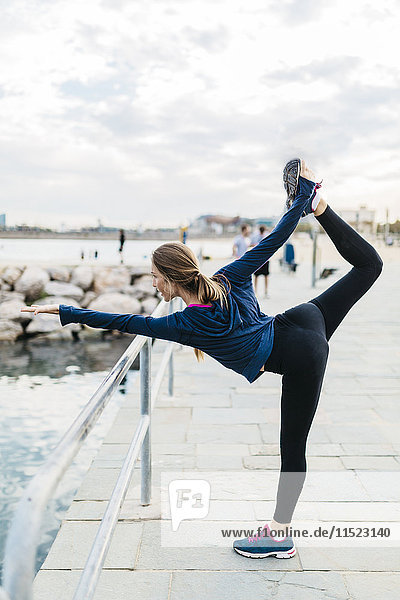Junge Frau beim Yoga posiert am Strand