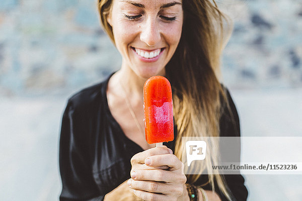 Lächelnde junge Frau mit Eis am Stiel