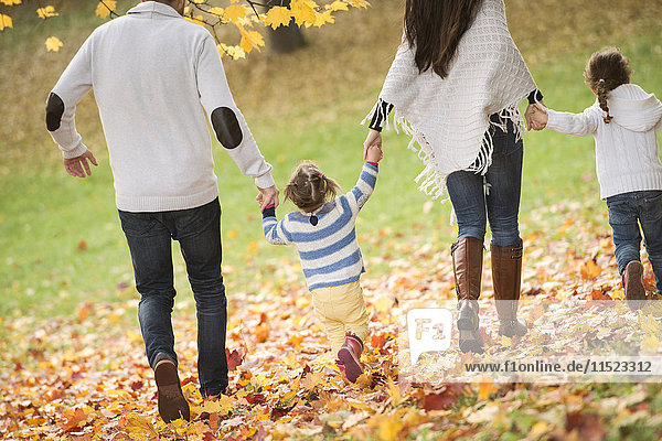 Glückliche Familie mit zwei Mädchen im Herbstlaub
