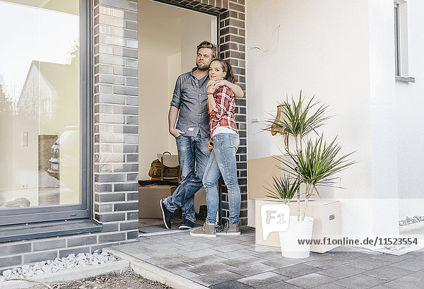 Ein glückliches Paar steht vor der Tür seines neuen Zuhauses.