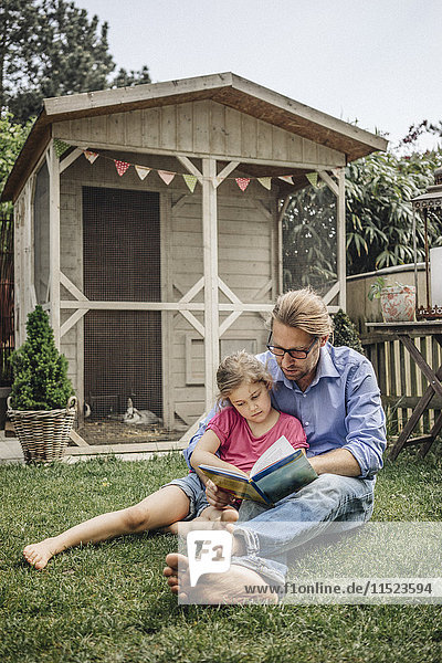 Vater Lesebuch mit Tochter im Garten