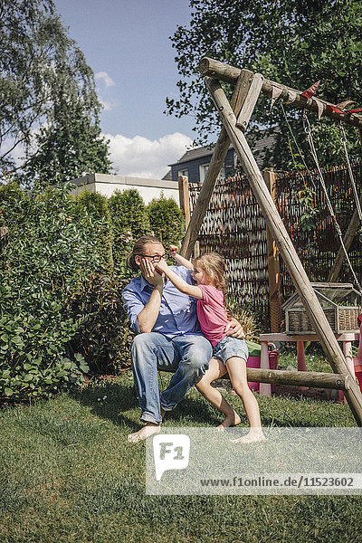Father playing with daughter in garden