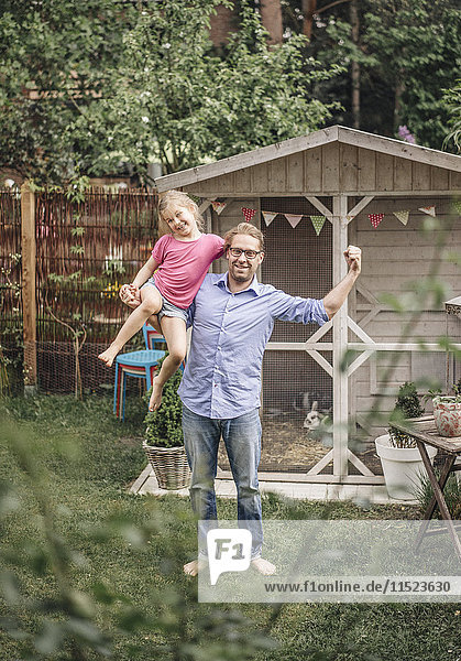 Father carrying daughter in garden