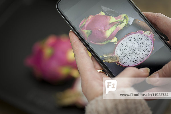 Hand holding cell phone with picture of dragon fruit