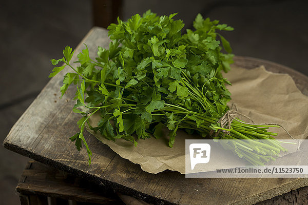 Bunch of flat leaf parsley on brown paper and wood