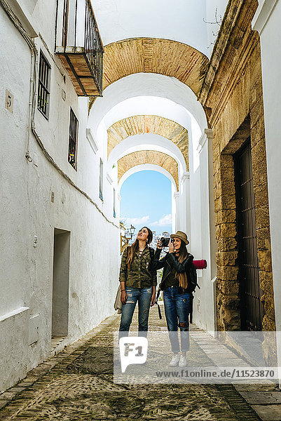 Spain  Andalusia  Vejer de la Frontera  two young women taking a photo in the alley El Callejon de las Monjas