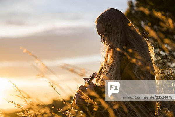 Junge Frau spielt Gitarre in der Natur