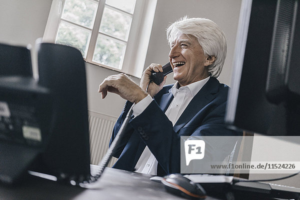 Laughing senior businessman on the phone in his office