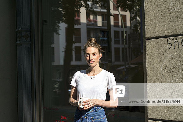 Young woman having a coffee break in front of a shop