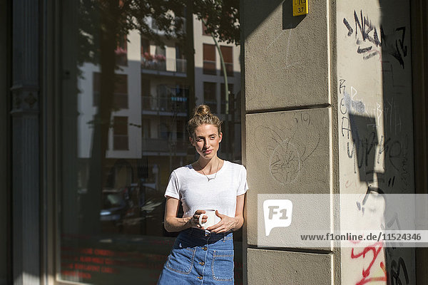 Junge Frau bei einer Kaffeepause vor einem Geschäft