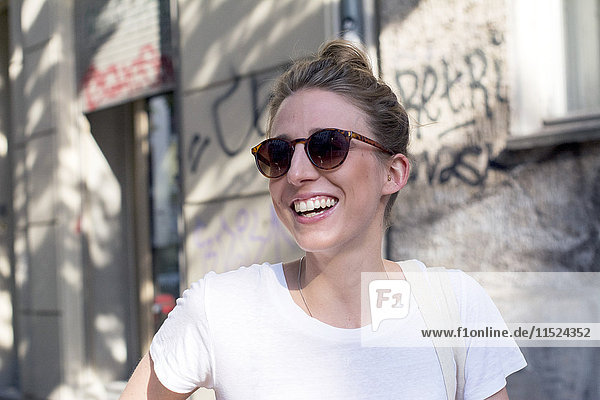 Porträt der lachenden jungen Frau mit Sonnenbrille