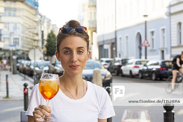 Porträt einer jungen Frau mit Aperitif im Straßencafé