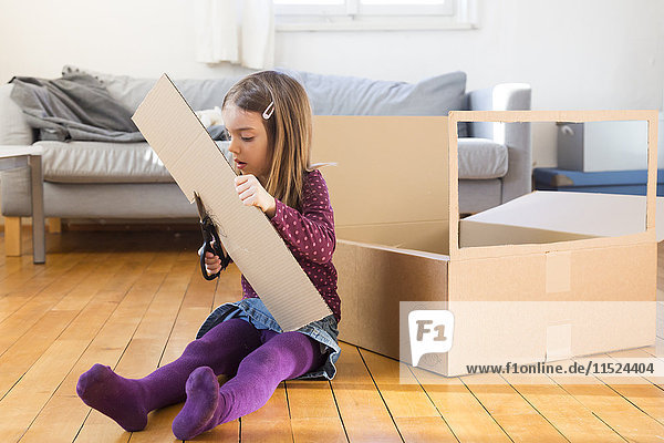 Girl tinkering with cardboard box at home