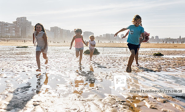 Gruppe von fünf Kindern beim gemeinsamen Laufen am Strand