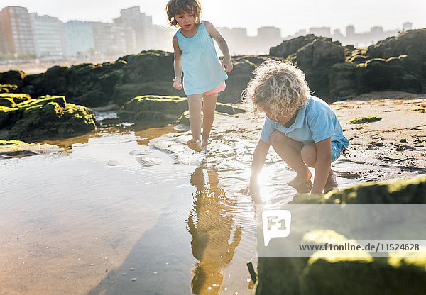 Kleiner Junge und Mädchen spielen zusammen am Strand.