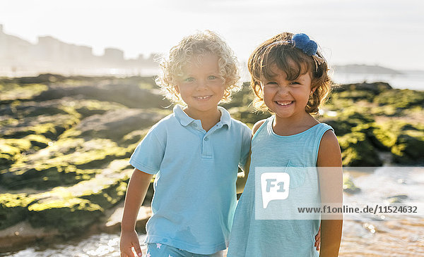 Portrait of happy little boy and girl side by side on the beach