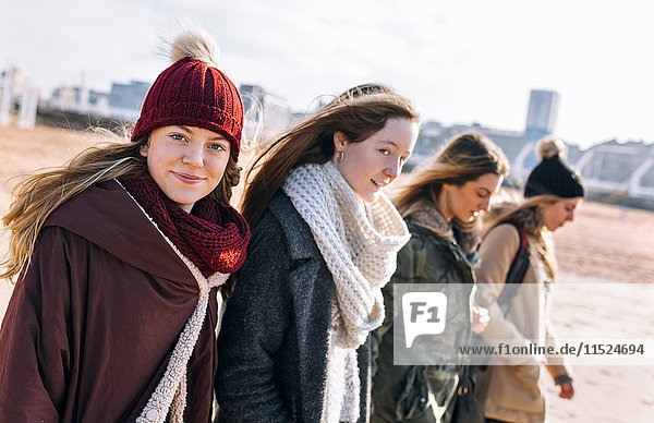 Portrait of teenage girl walking on the beach with her friends in winter