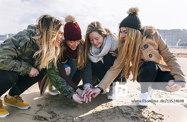 Vier Freunde  die sich am Strand die Hände reichen.