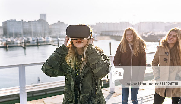 Teenage girl using wearing VR glasses while her friends watching her