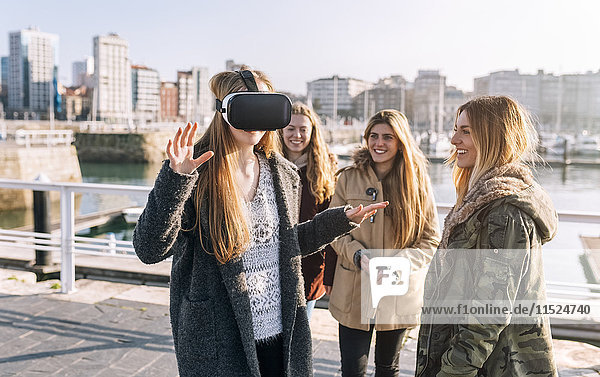 Teenager-Mädchen  das eine VR-Brille trägt  während ihre Freunde sie beobachten.