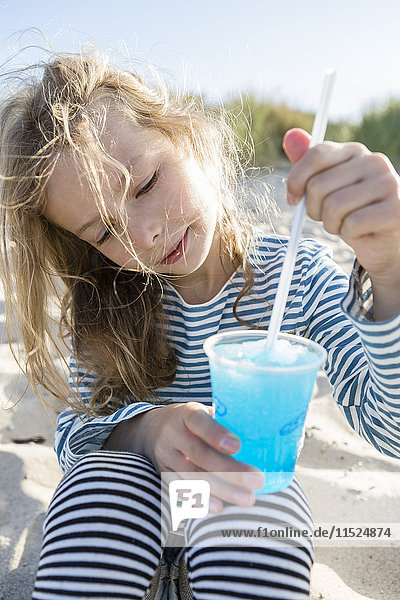 Mädchen am Strand Rühren blau gefrorenes Getränk mit einem Strohhalm