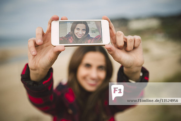 Fotografie einer jungen Frau  die einen Selfie auf dem Display eines Smartphones zeigt.