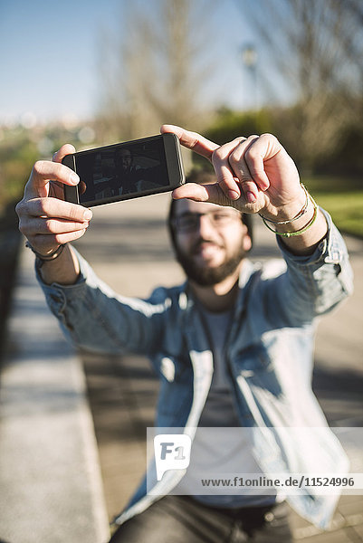 Lächelnder junger Mann  der einen Selfie nimmt.