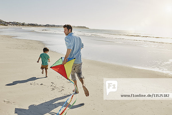 Vater und kleiner Sohn beim Drachenspielen am Strand