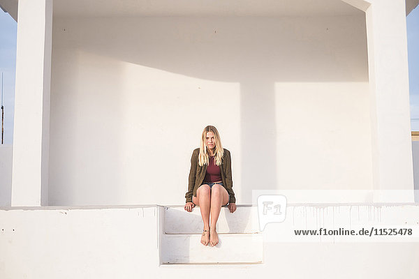 Spanien  Teneriffa  Portrait einer jungen blonden Frau auf einer Treppe sitzend