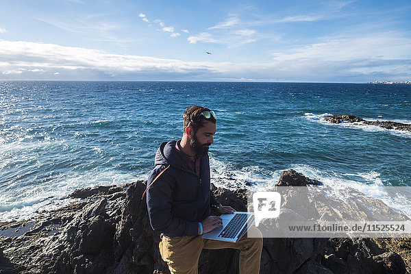 Spanien  Teneriffa  Mann mit Laptop vor dem Meer