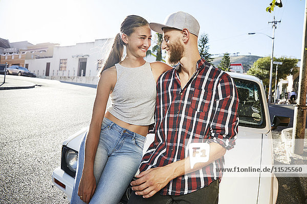 Young couple in love sitting on car bonnet