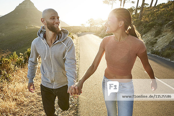 Südafrika  Kapstadt  glückliches junges Paar  das bei Sonnenuntergang Hand in Hand geht