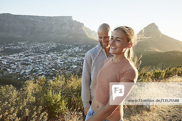 Südafrika  Kapstadt  glückliches junges Paar am Straßenrand bei Abenddämmerung