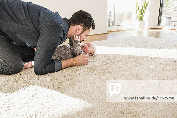 Vater und Sohn spielen zu Hause auf dem Teppich.