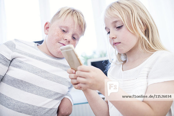 Brother and sister using cell phone together