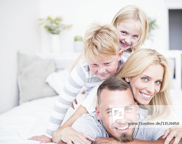 Portrait of smiling family lying in bed on top of each other