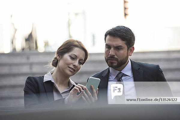 Businesswoman sharing cell phone with colleague