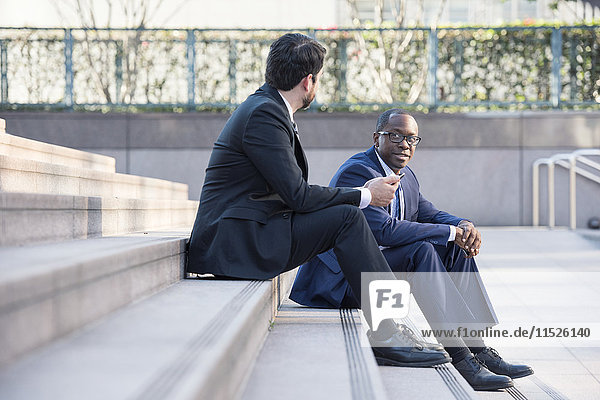 Two businessmen sitting on stairs talking
