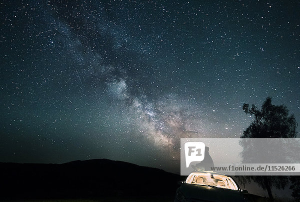 Austria  Mondsee  silhouette of man sitting on car roof under starry sky