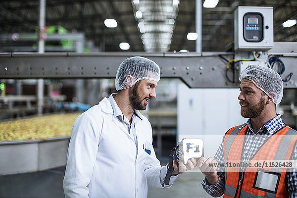 Two men talking in food processing plant