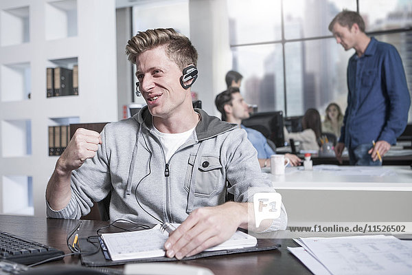 Young man at desk in office wearing a headset