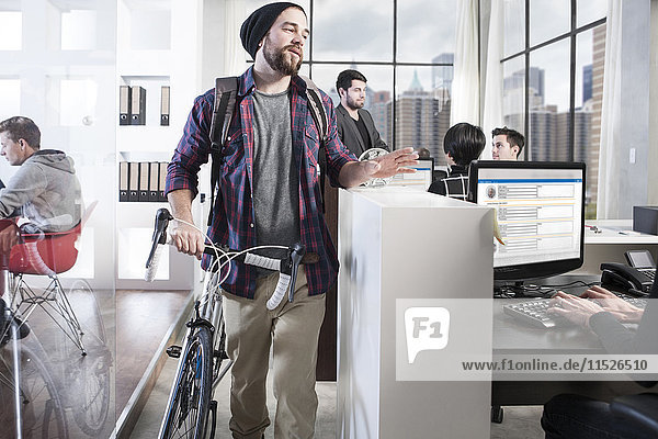 Lässiger Mann mit Fahrrad im modernen Büro