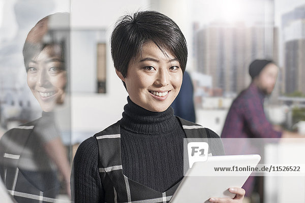 Portrait of smiling woman holding a tablet in office